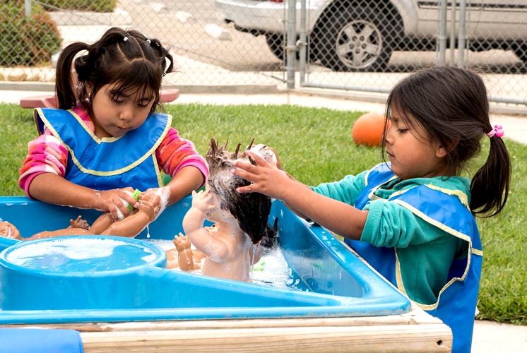 dos niñas bañando muñecas