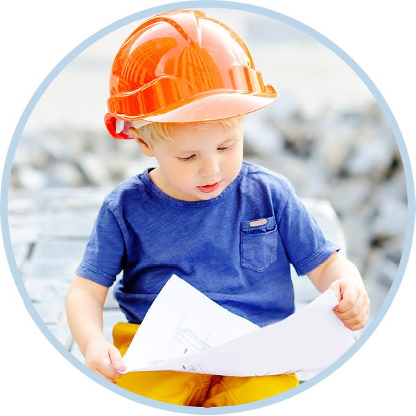 Small child reading building plans with a hard helmet on