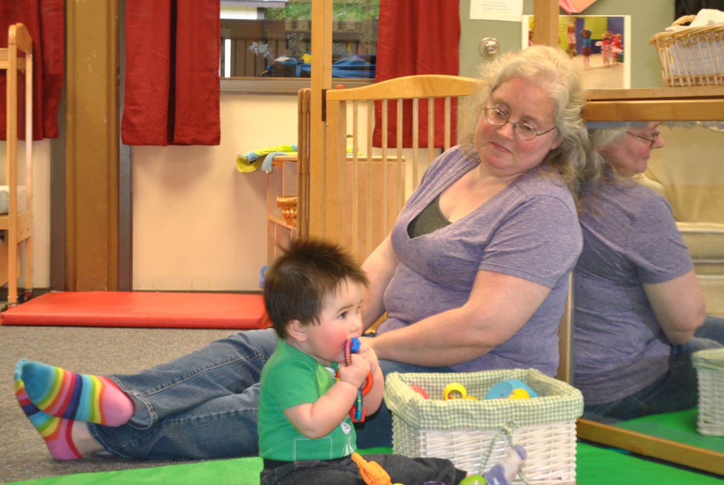 Caretaker keeping tabs on toddler playing beside her.