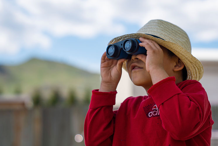 A boy looks at the sky through binoculars