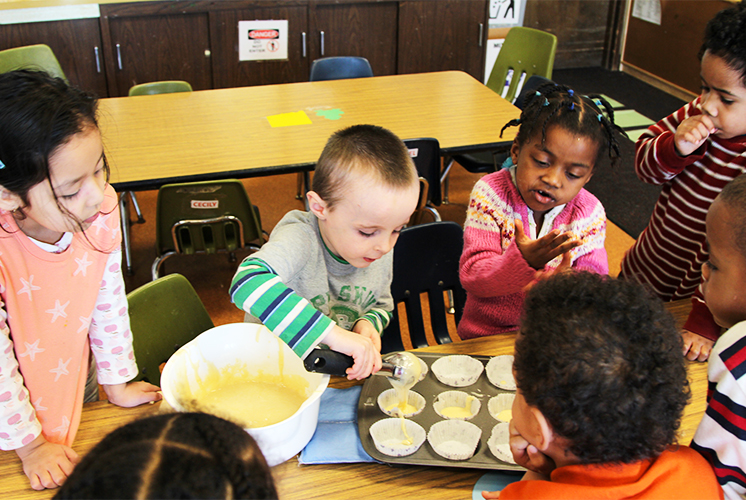 Kids gather around to mix batter at table