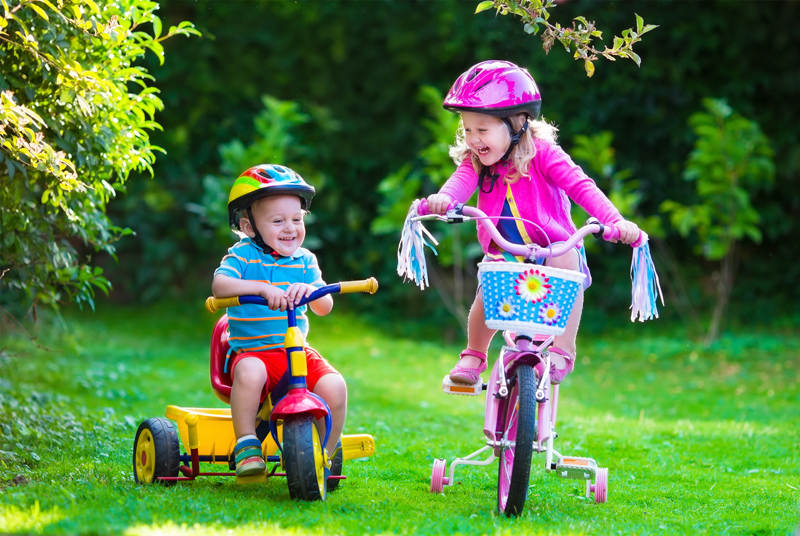 Niños con cascos mientras andan en bicicleta afuera.