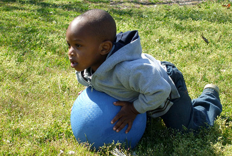 un niño acostado en una pelota inflable en el césped