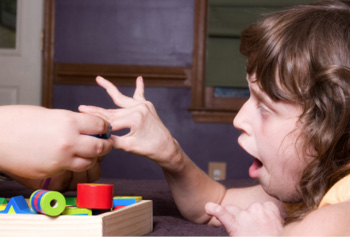 Little girl with special needs reaches for a toy