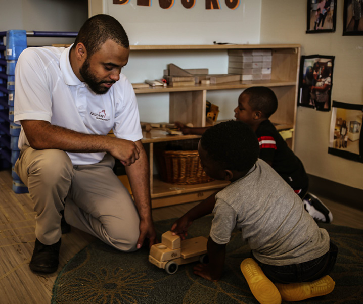 Man and two kids playing with a wooden toy truck