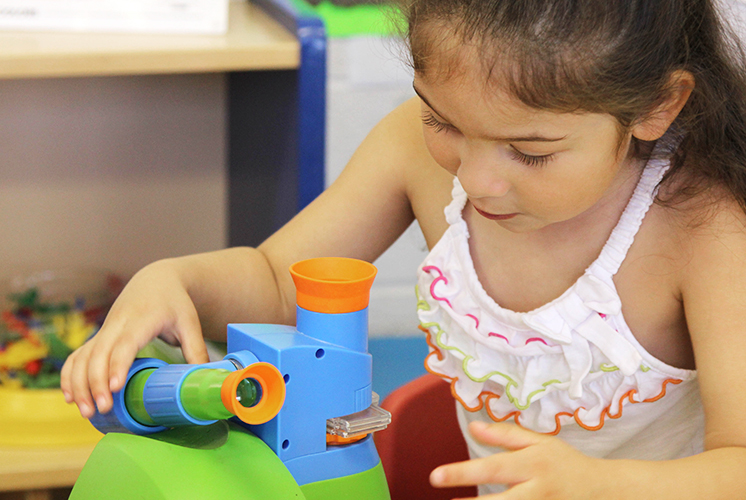 Niña ajustando un microscopio