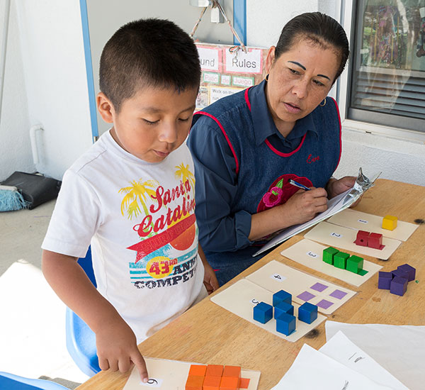 Teacher with child at a workstation