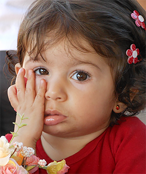 Niña tocándose un lado de la boca