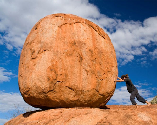 Woman trying to move a boulder