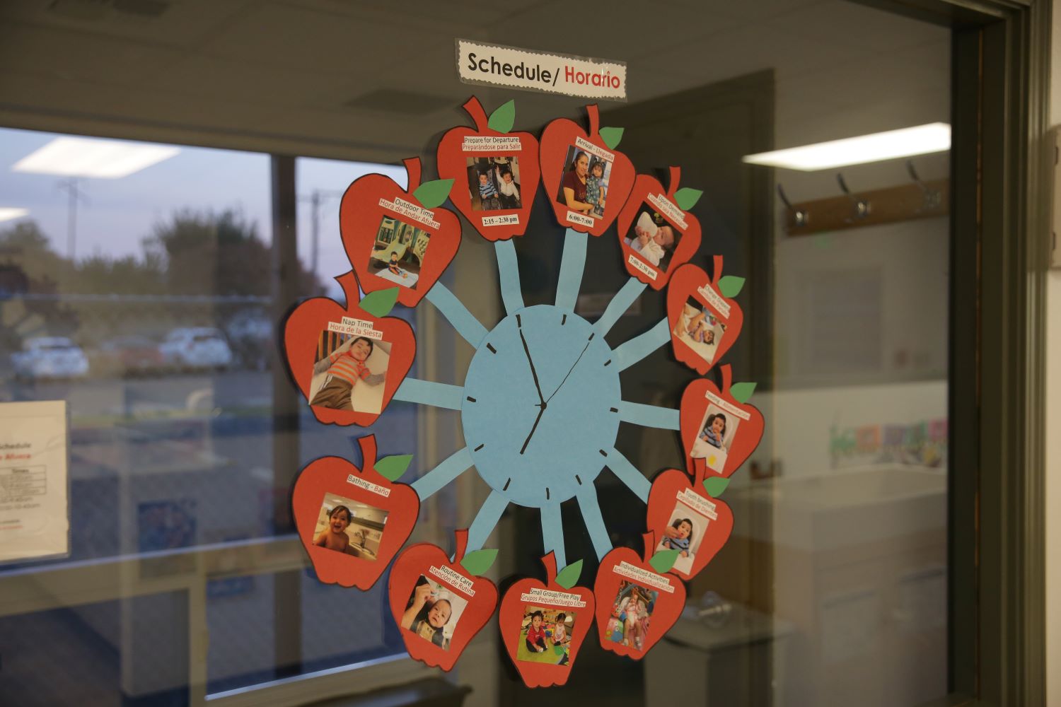 A large cutout of a clock with a schedule taped to a window.