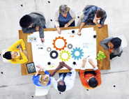 Overhead view of people seated around a table with a colorful chart in the middle.