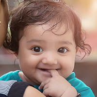 a toddler girl smiles over adult's shoulder