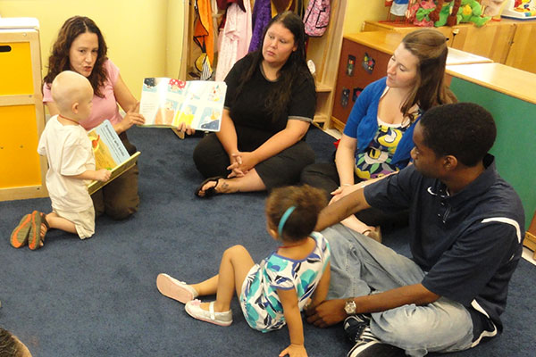 Padres con niños sentados en un círculo leyendo un libro