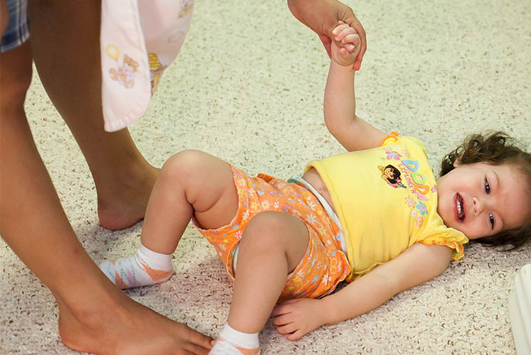 a child cries on the floor while caregiver holds her hand