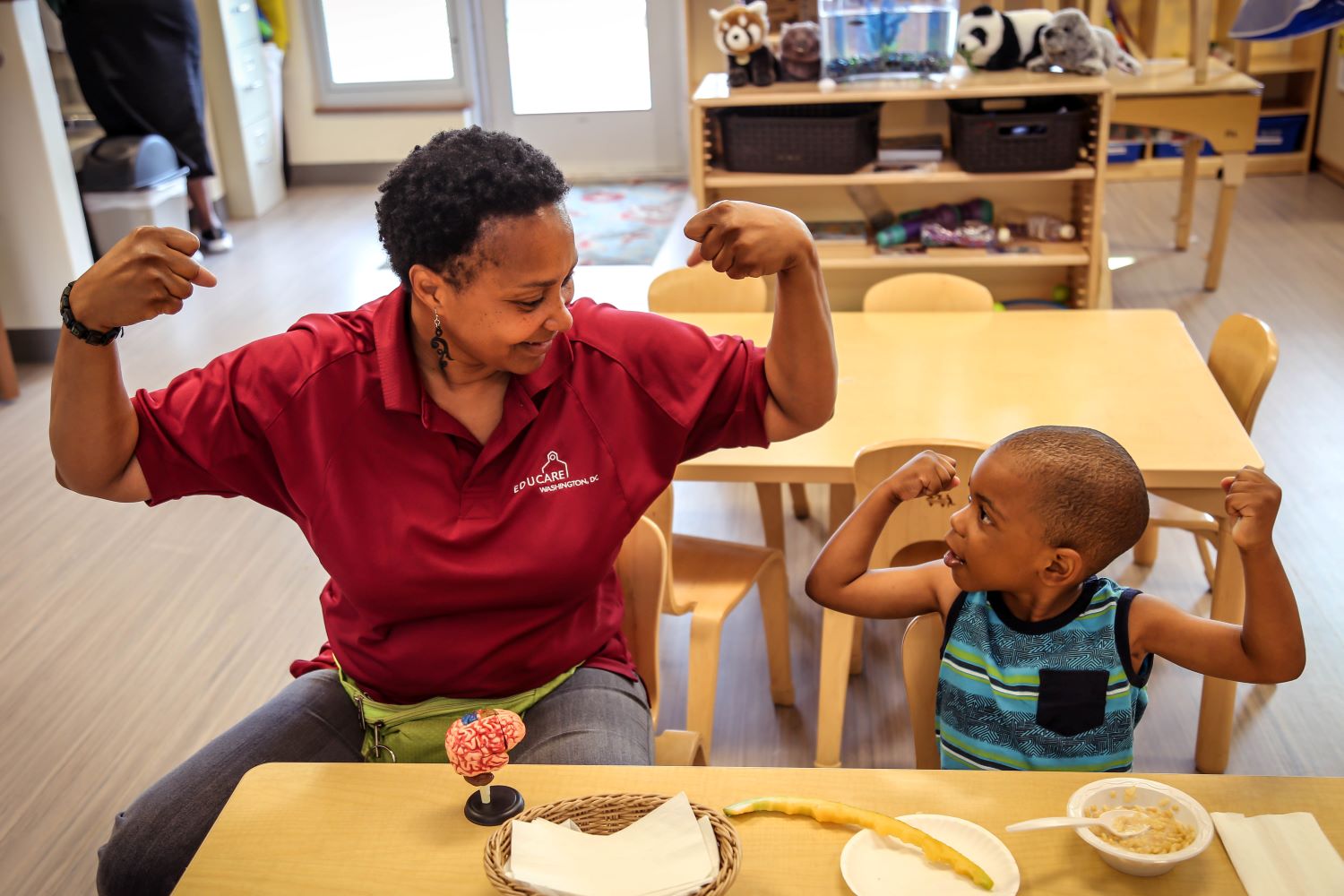 Teacher and child feeling strong by both raising their arms to show off their muscles.