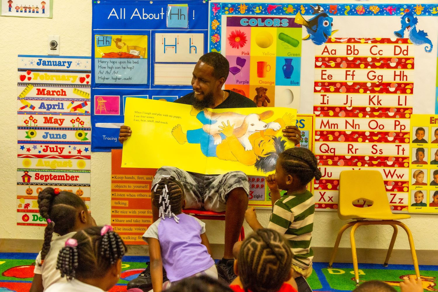 Teacher holding a large picture of a child playing with a puppy.