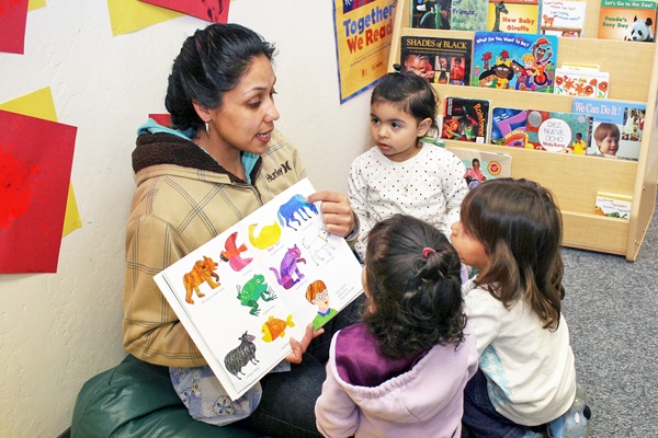 Maestra leyéndoles a unos niños pequeños