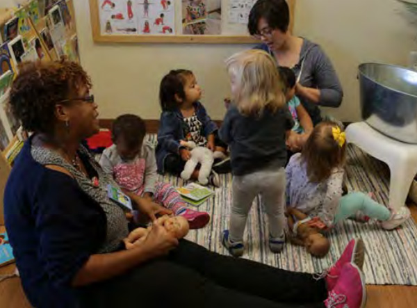 Teachers sitting on the floor with toddlers