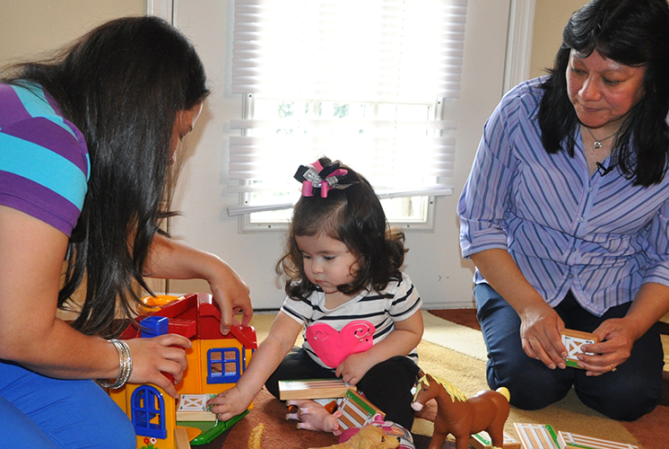 two adults play with a toddler