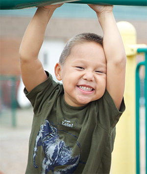 Toddler boy swinging on a playset