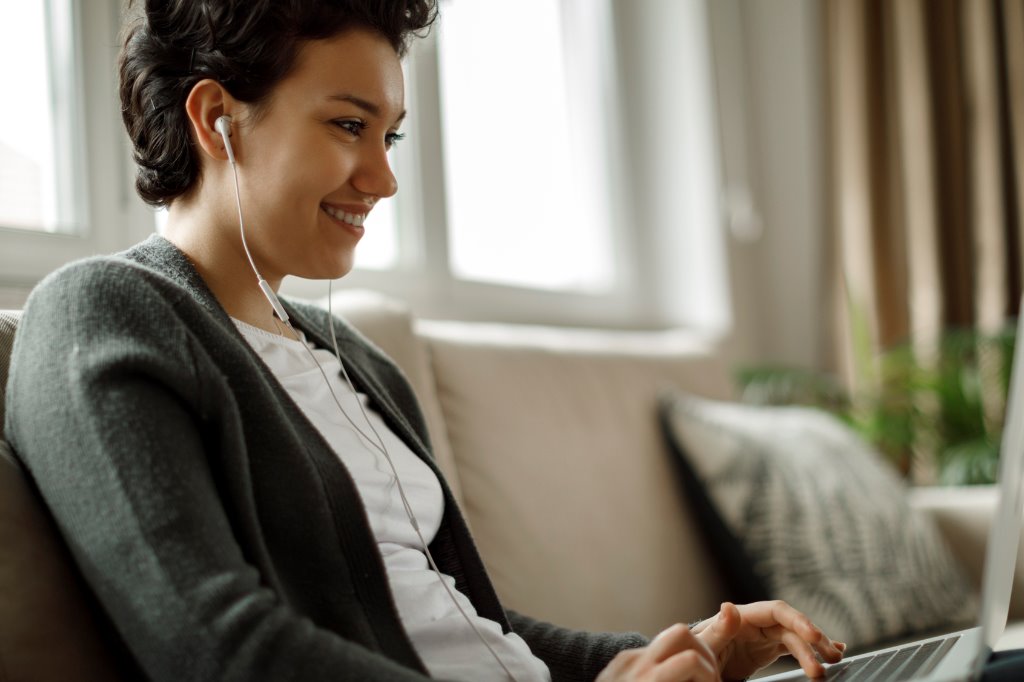 Woman using her laptop while wearing headphones.