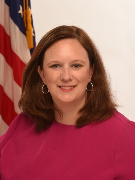 Foto de perfil de Katie Hamm frente a la bandera de Estados Unidos.