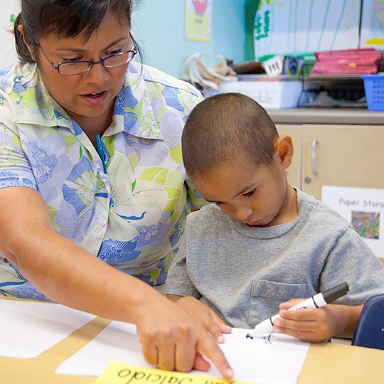 teacher helping boy with marker