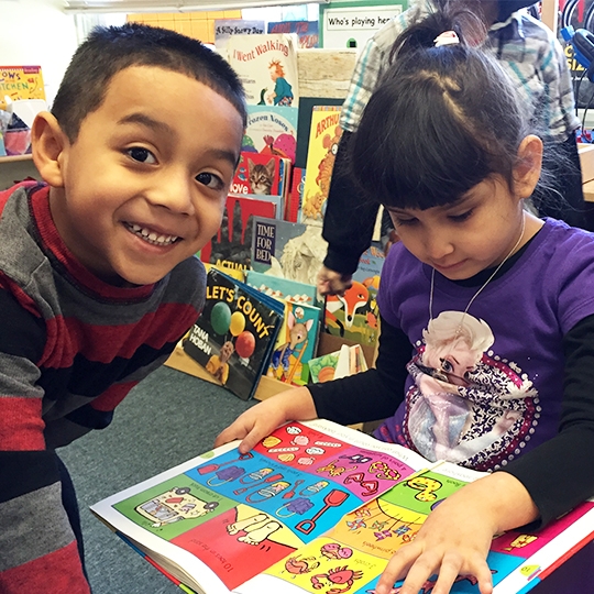 Two children read a book